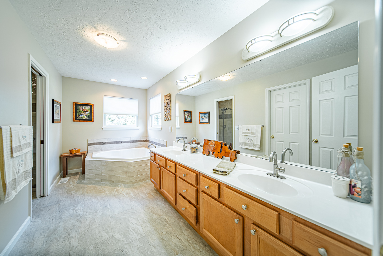 This West Lafayette primary bathroom remodel features a tiled walk-in shower, brushed nickel finishes, a corner bench, and elegant floor-to-ceiling tilework.
