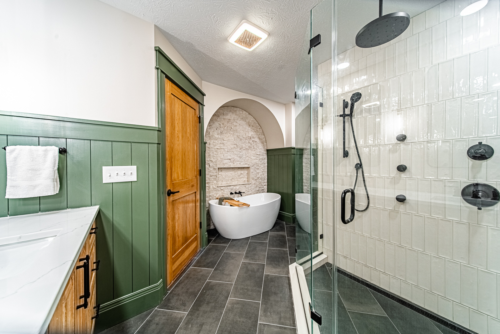 This Frankfort bathroom remodel features a rustic oak vanity, a spa-style walk-in shower, and a freestanding tub with a custom stone accent wall—designed for comfort, luxury, and everyday relaxation.