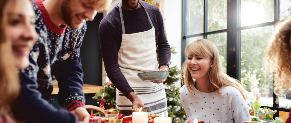 Friends and family gathered around a kitchen table decorated for Christmas, illustrating a warm, inviting holiday atmosphere in a well-designed kitchen.