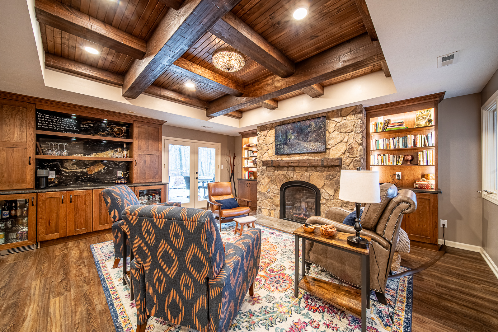 Cozy sitting area in rustic basement remodel with fireplace and tray ceiling with wood beams.
