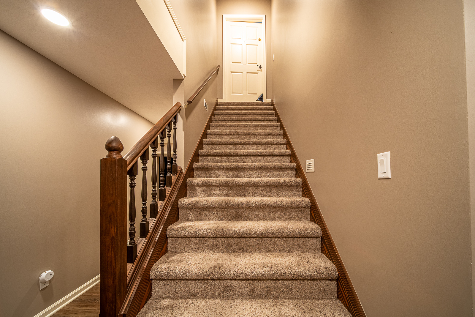 Graceful stairs with wood railing in the remodeled basement on Ripple Creek Drive.